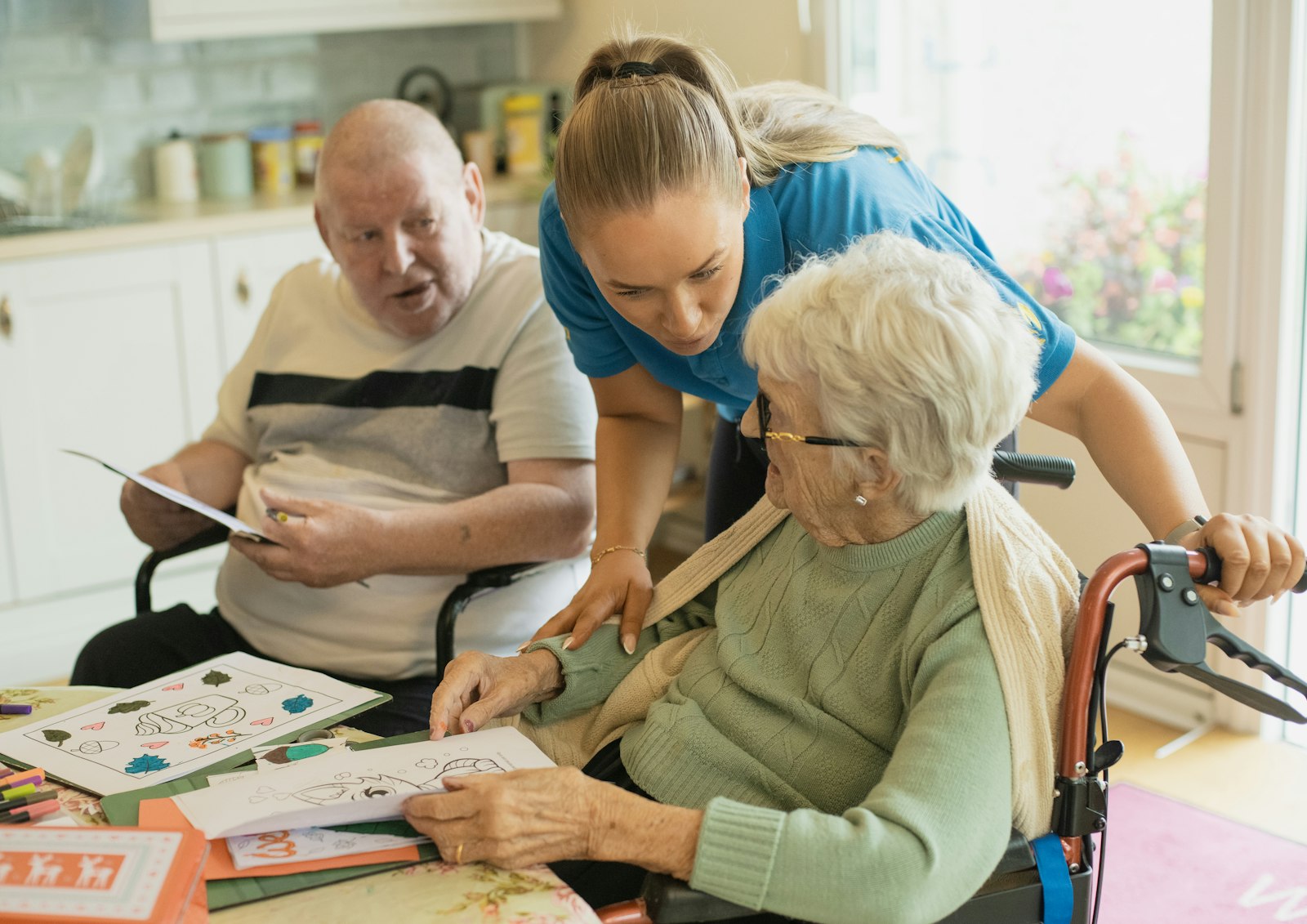 Support worker helping an elderly man get up from a chair at home