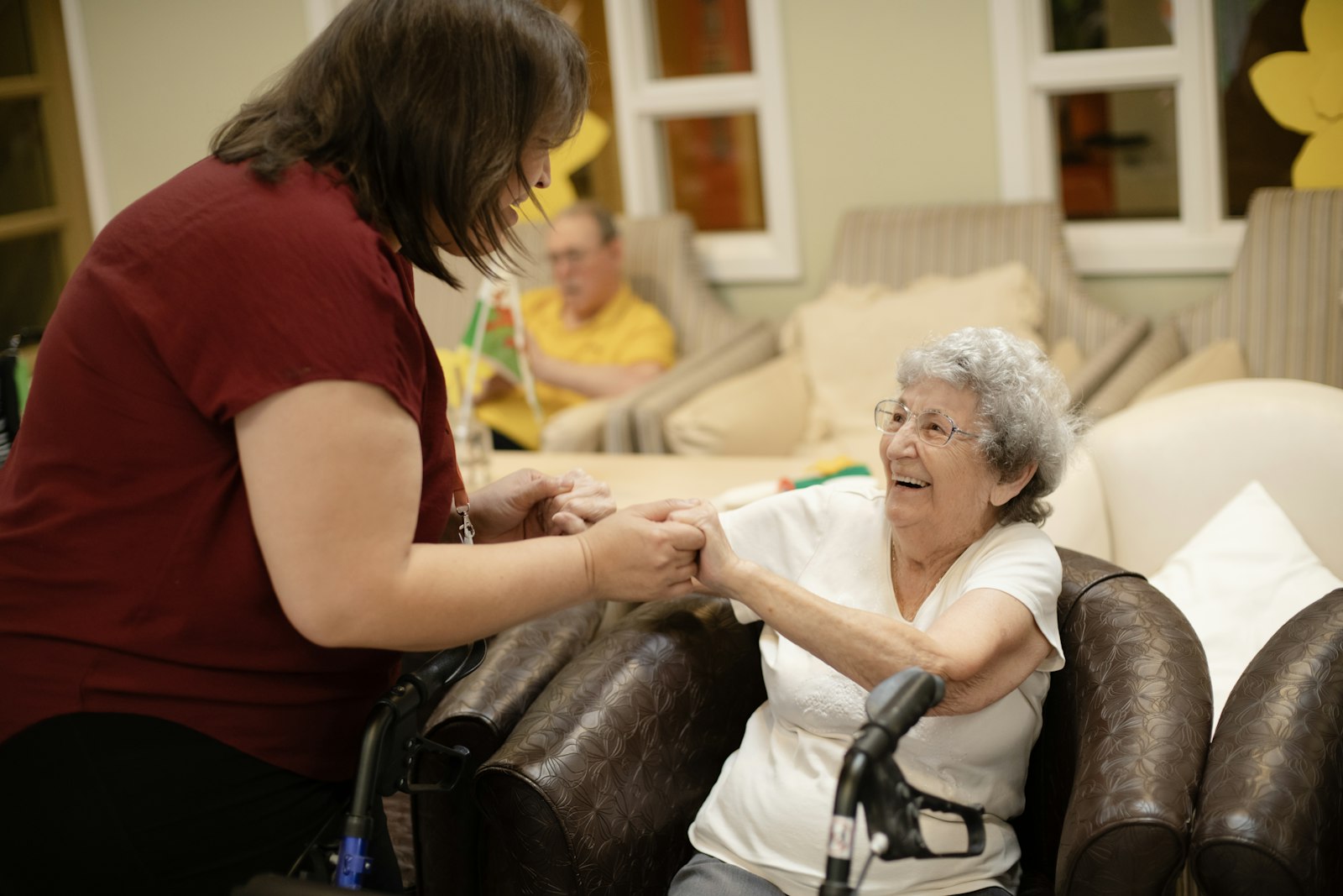 Support worker holding hands with a smiling client at home