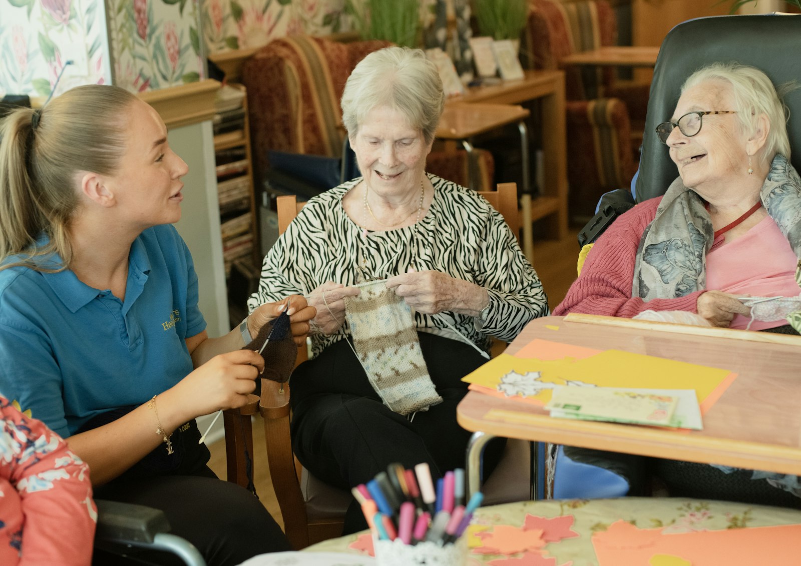 Support worker helping participants with a knitting activity